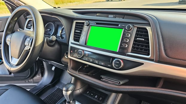 An interior view of a modern vehicle showcasing the dashboard. The green screen display is perfect for advertising or information. Highlighting transportation and tech integration.