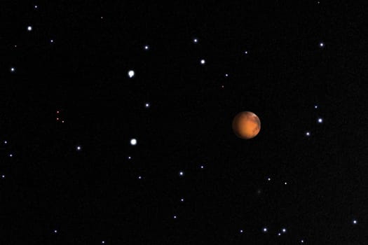 A digitally rendered image of the planet Mars floating in deep space, surrounded by numerous bright stars scattered across a dark cosmic background. The red planet stands out with its distinct surface features, offering a captivating view for use in science fiction, astronomy, or educational contexts.