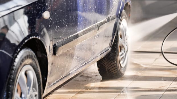 High pressure water cleaning car side in self-service car wash station