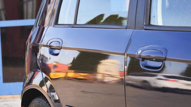 Polished car reflecting surrounding buildings after car wash service
