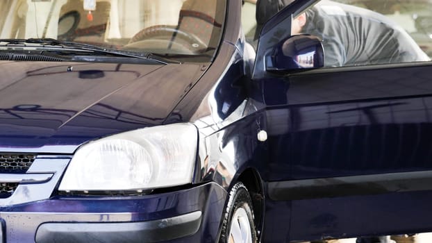 Professional car wash worker cleaning vehicle interior with microfiber cloth, providing high-quality detailing service