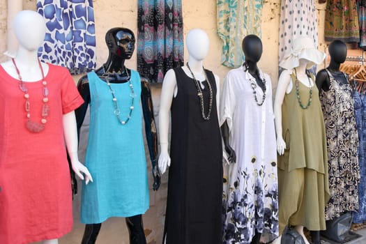 Rodas.Greece May 22, 2025: An inviting outdoor shop facade adorned with a wide array of summer clothing on mannequins and hangers, drawing in potential customers who are seen engaging with