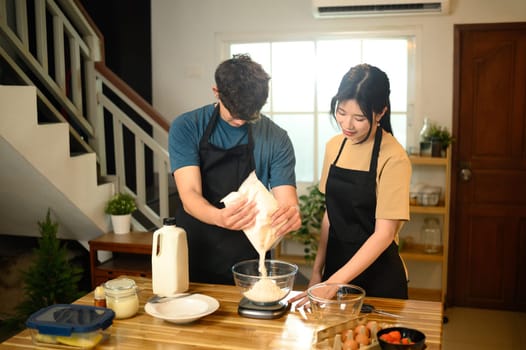 Young couple preparing pancake batter together in a kitchen.