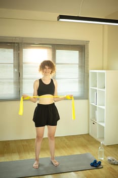 Athletic woman working out with a resistance band in bright living room.