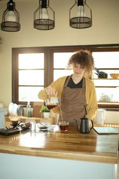 Young woman in casual clothes and apron enjoying a coffee making routine at home.