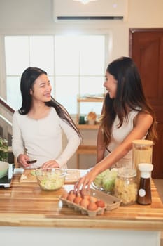 Happy mother and daughter preparing a meal together in the kitchen.