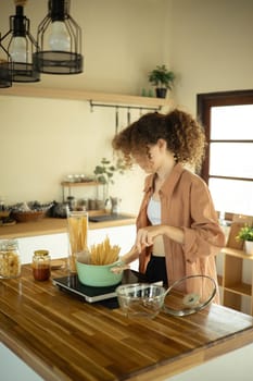 Young woman in casual clothes preparing a meal in a cozy kitchen.