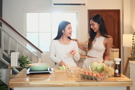 Happy mother and daughter preparing a meal together in the kitchen.