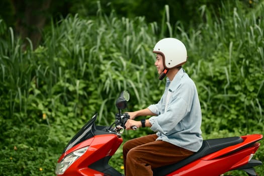 Smiling male motorcyclist enjoying a relaxed ride through a suburban neighborhood..