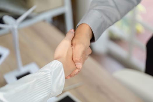 A close-up of two professionals shaking hands, emphasizing a commitment to ESG initiatives in a modern office environment.