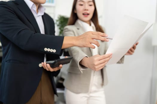 Two business professionals engaged in a strategic discussion, reviewing project documents and collaborating in a bright office environment.