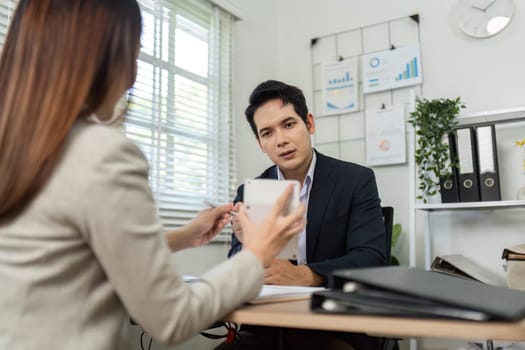 A focused business meeting where a man and woman discuss financial strategies and share insights in a modern office setting.
