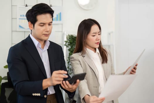 Two professionals review project documents, discussing strategies and insights in a bright, modern office environment.
