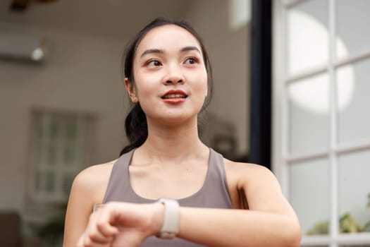 A fitness-focused woman checks her smartwatch, smiling and enjoying her workout experience, promoting positivity and health.