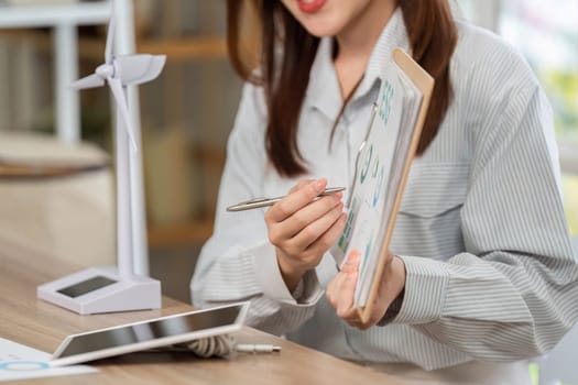 A businesswoman discusses renewable energy metrics while holding a clipboard, highlighting ESG initiatives.