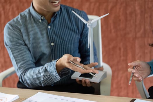 A man and woman discuss ESG initiatives, using a wind energy model to illustrate sustainable practices in their business strategy.
