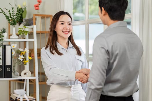 A businesswoman smiles while shaking hands with a colleague, symbolizing a successful partnership.