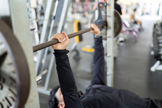 A determined man performs a bench press exercise, showcasing strength training and fitness commitment in the gym.