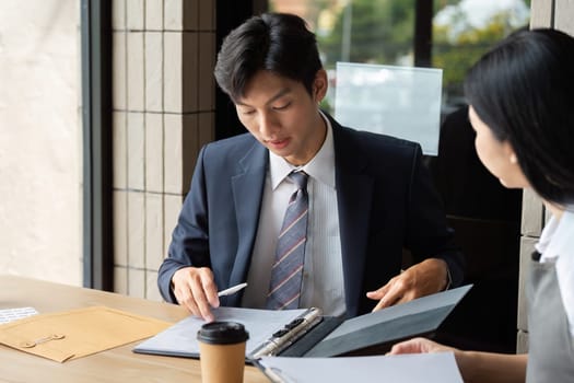 Two professionals engage in a focused discussion, reviewing documents and collaborating on business strategies in a contemporary workspace.