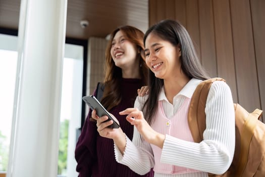 In a stylish academic environment, both students interact enthusiastically with their smartphones while supporting each other's learning.
