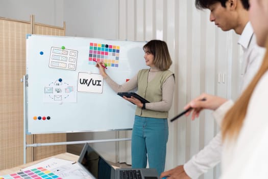 In a professional setting, a woman outlines UX UI ideas while her colleagues engage in the creative brainstorming process, showcasing collaboration and innovative thinking.