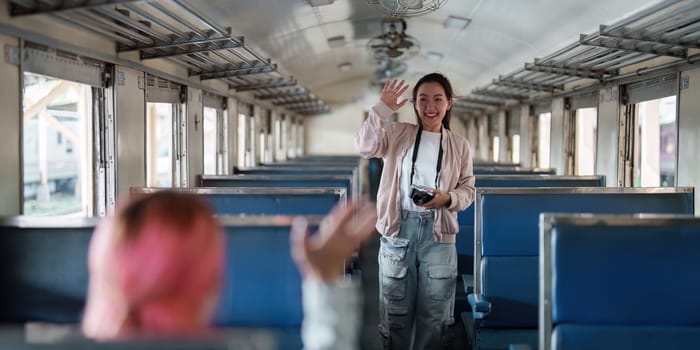 A cheerful woman greets her friend in a nostalgic train carriage, blending travel and camaraderie as they embark on an adventure together.