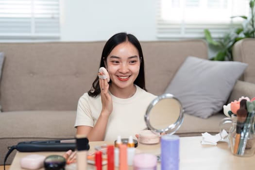 A vibrant woman efficiently applies makeup during her morning routine at home, surrounded by an array of beauty products to enhance her look.