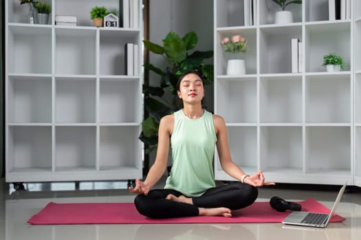 In a peaceful yoga space, a woman practices meditation, surrounded by calm, showcasing her journey towards mindfulness and stress relief through deep focus and breathing.