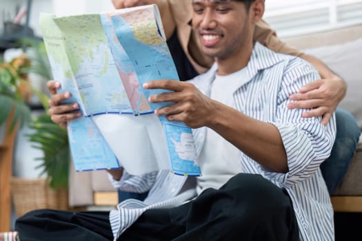The couple is engaged in a light-hearted moment as they look at a map, filled with smiles and laughter, excited for their upcoming trip.