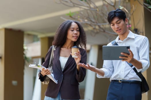 vibrant conversation between woman holding a coffee cup and man showing information on tablet highlights the synergy of eco-friendly practices and community.