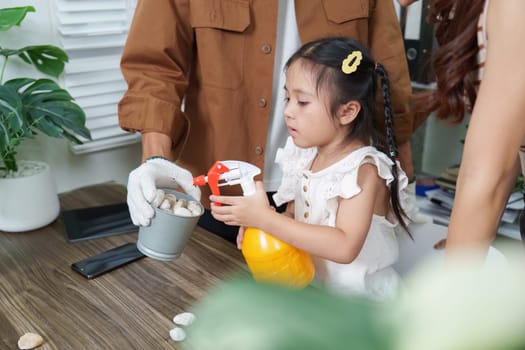 A little girl, eager to nurture the environment, uses a spray bottle to care for her plants. This scene highlights the importance of sustainability and eco-consciousness in child development.