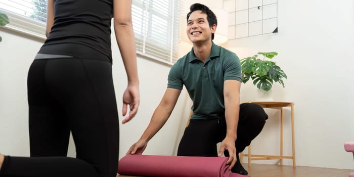 A couple joyfully rolls out their yoga mats, preparing for a shared wellness practice in a bright indoor space.