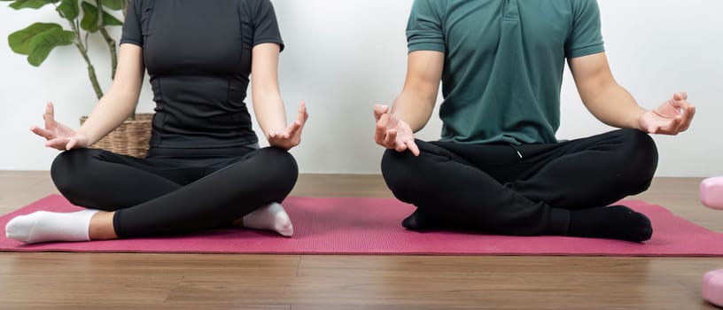 A couple in a meditative pose, promoting wellness and mindfulness in a serene indoor environment.