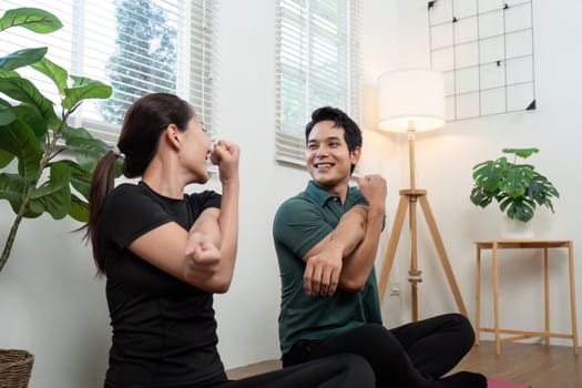 A couple practicing wellness stretches together in a cozy indoor setting, promoting health and connection.