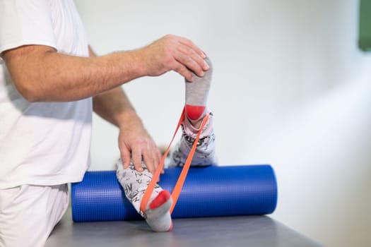 Therapist assisting with leg stretching using a resistance band during physical rehabilitation therapy session.