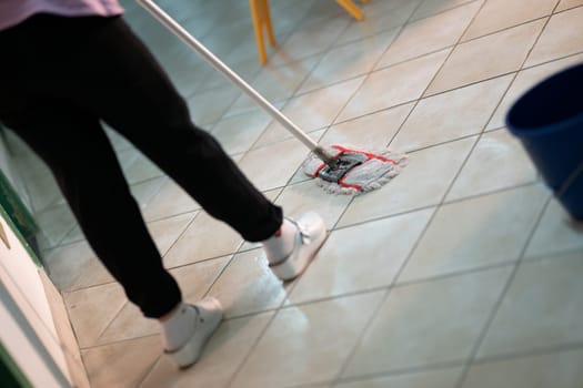 Female janitor standing in a hospital corridor with mop and bucket, symbolizing cleanliness and hygiene.