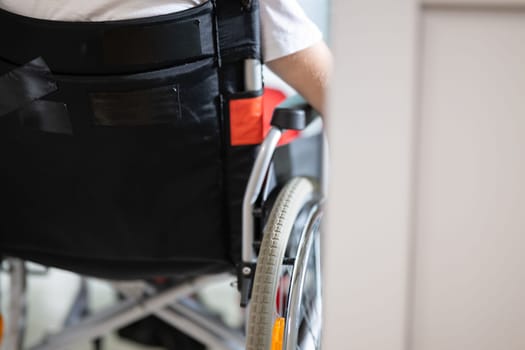 Young teenage boy smiling while sitting in a wheelchair in a hospital hallway. Rehabilitation and positivity concept