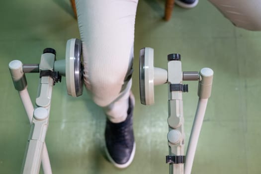 Top down view of a person using a rehabilitation machine for leg therapy, focusing on muscle training and mobility.
