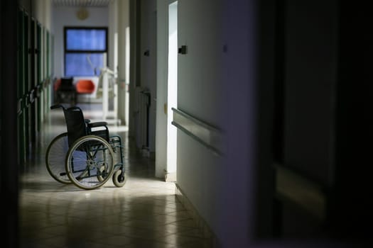 Unattended wheelchair positioned in a bright hospital corridor. Concept of accessibility and patient transport.