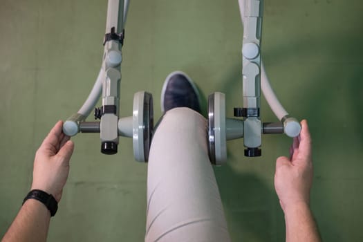 Top down view of a person using a rehabilitation machine for leg therapy, focusing on muscle training and mobility.