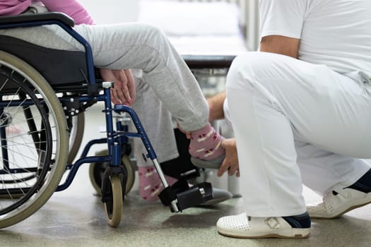 Senior woman doing physical exercises with the help of a smiling therapist. Concept of elderly rehabilitation and movement recovery.