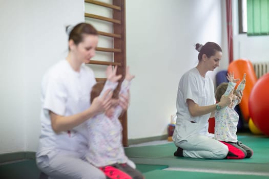 Female physiotherapist helping a young child with physical exercises in a rehabilitation center. Pediatric therapy and development concept.