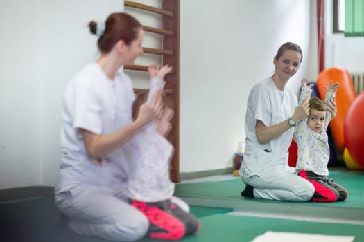 Female physiotherapist helping a young child with physical exercises in a rehabilitation center. Pediatric therapy and development concept.