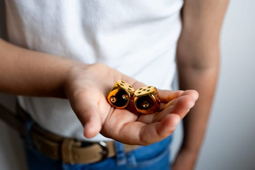 Young hispanic female holding golden dice in hand.