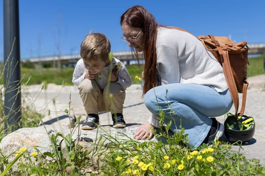 Woman and boy observing plants outdoors on a sunny day