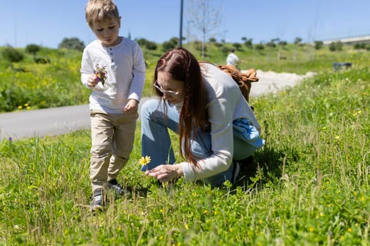 Mother and son enjoying a sunny day picking wildflowers in a meadow