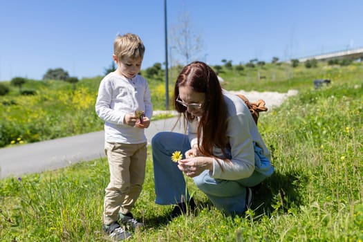 Mother and son enjoying a sunny day picking flowers in a park