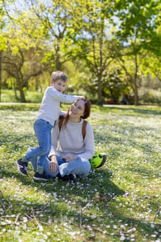 Happy mother and son enjoying a sunny spring day in a park full of daisies