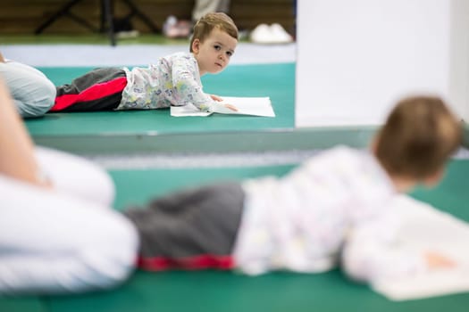 Young boy on a therapy mat during a physiotherapy session, engaging in a supervised stretching activity.