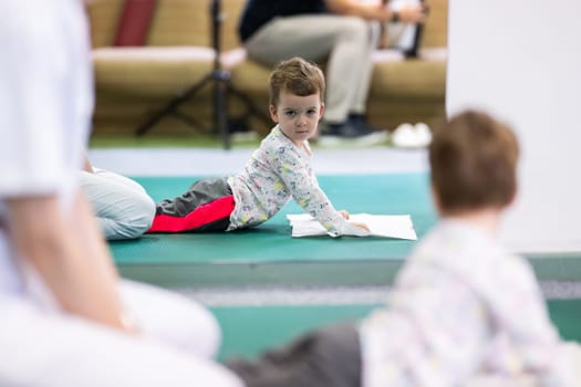 Young boy on a therapy mat during a physiotherapy session, engaging in a supervised stretching activity.